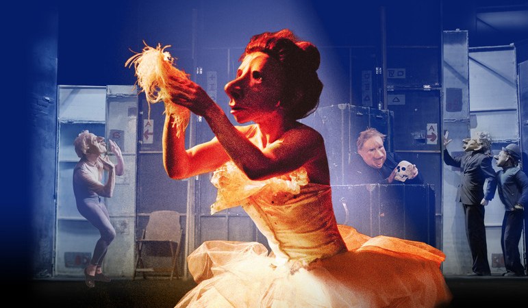 Maskierte Darsteller in einer Theaterszene. Im Vordergrund kniet eine Figur im Scheinwerferlicht, während im Hintergrund weitere Darsteller agieren., © Theaterhaus Stuttgart e.V. Maskierte Darsteller in einer Theaterszene. Im Vordergrund kniet eine Figur im Scheinwerferlicht, während im Hintergrund weitere Darsteller agieren., © Theaterhaus Stuttgart e.V.