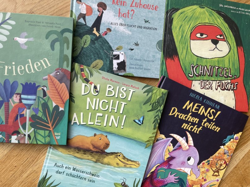 F&uuml;nf Kinderb&uuml;cher mit farbenfrohen Covern liegen auf einem Holztisch und laden zum Lesen ein., &copy; Labyrinth