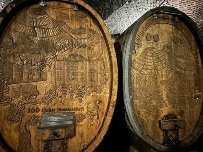 Zwei große, kunstvoll geschnitzte Weinfässer in einem historischen Weinkeller. Die Fässer zeigen detaillierte Gravuren von Weinreben und Gebäuden., © Weingenuss Stuttgart Zwei große, kunstvoll geschnitzte Weinfässer in einem historischen Weinkeller. Die Fässer zeigen detaillierte Gravuren von Weinreben und Gebäuden., © Weingenuss Stuttgart