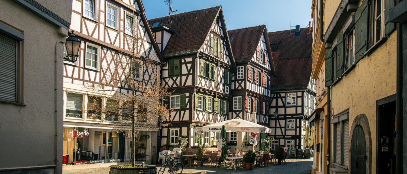 Fachwerkh&auml;user am Schorndorfer Marktplatz. Ein Caf&eacute; mit Sonnenschirmen und Tischen im Freien l&auml;dt zum Verweilen ein., &copy; Stuttgart-Marketing GmbH, Sarah Schmid