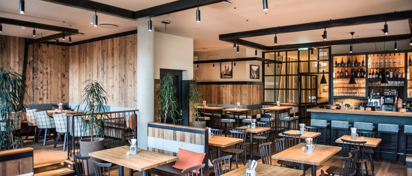 Modern brewery with wooden furniture, bar and plants. Cozy atmosphere with wooden walls and stylish lighting., © Andreas Engelhard - Engelhard Photography