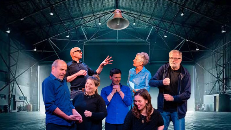 Sieben Personen einer Improtheatergruppe agieren lebhaft in einer großen, leeren Halle mit Stahlträgern und Beleuchtung., © Veranstalter Sieben Personen einer Improtheatergruppe agieren lebhaft in einer großen, leeren Halle mit Stahlträgern und Beleuchtung., © Veranstalter