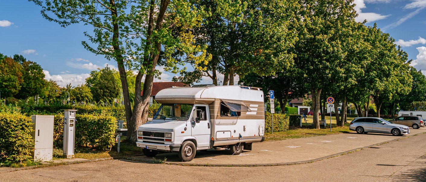Ein Wohnmobil steht auf einem Stellplatz in Marbach am Neckar, umgeben von Bäumen und geparkten Autos. Der Himmel ist blau mit einigen Wolken., © Stuttgart-Marketing GmbH, Thomas Niedermüller Ein Wohnmobil steht auf einem Stellplatz in Marbach am Neckar, umgeben von Bäumen und geparkten Autos. Der Himmel ist blau mit einigen Wolken., © Stuttgart-Marketing GmbH, Thomas Niedermüller