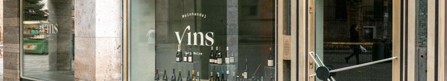 Shop window of the wine shop 'Vins Gute Weine' with wine bottles on display and a bench in front of it., &copy; SMG Stuttgart Marketing GmbH - Sarah Schmid