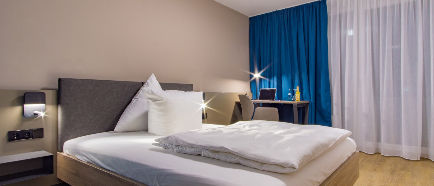 A modern single room with a bed, a desk, and blue curtains. The room feels bright and inviting., &copy; otel Berlin aZIS Hotel BetriebsGmbH