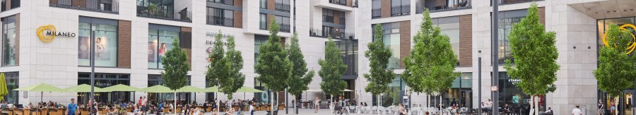 The Milaneo shopping center on Mail&auml;nder Platz with modern buildings, trees and a fountain in the foreground. People sit and walk., &copy; Peter Oppenl&auml;nder