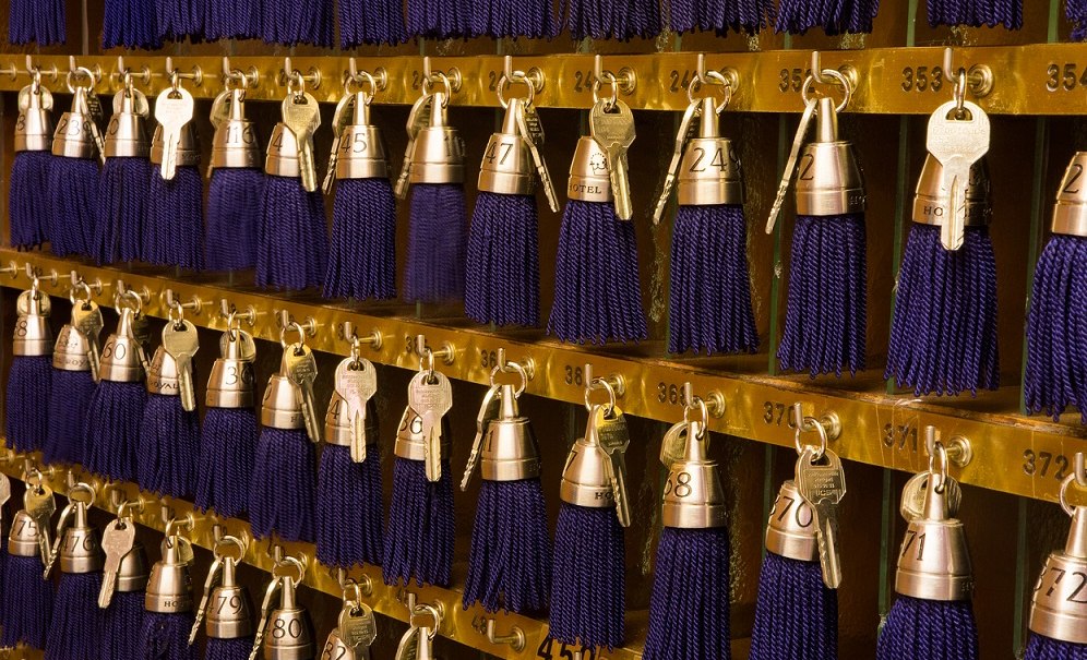 Hotelrezeption mit goldenen Haken, an denen Schlüssel mit blauen Quasten hängen. Die Schlüssel sind nummeriert., © Hotel Royal Hotelrezeption mit goldenen Haken, an denen Schlüssel mit blauen Quasten hängen. Die Schlüssel sind nummeriert., © Hotel Royal