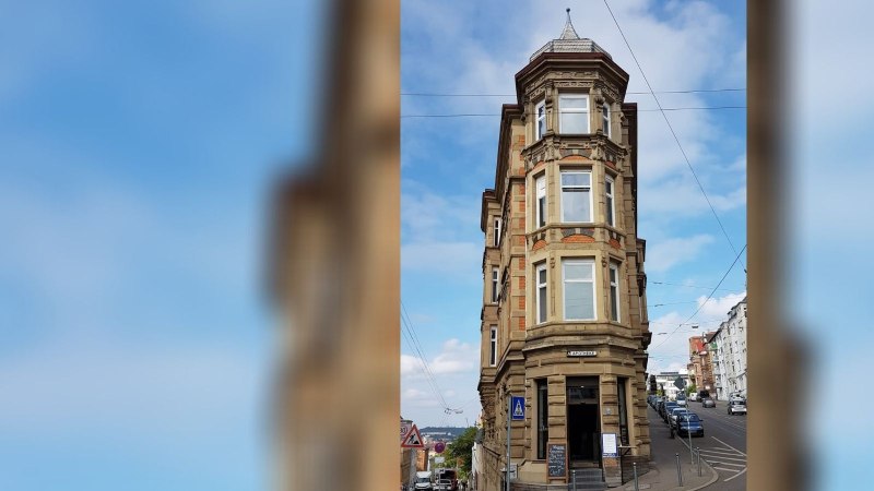 Historisches Eckgebäude mit Apotheke im Erdgeschoss, umgeben von Straßen und Autos, unter blauem Himmel., © SMG Historisches Eckgebäude mit Apotheke im Erdgeschoss, umgeben von Straßen und Autos, unter blauem Himmel., © SMG