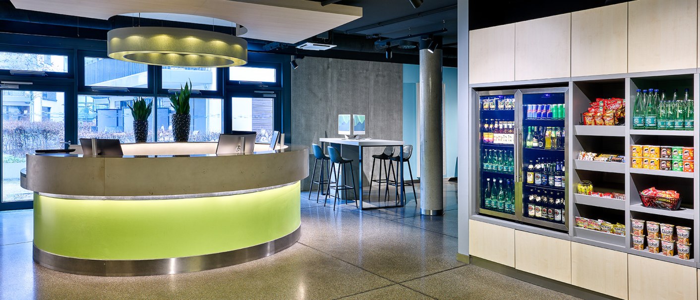 Modern reception with illuminated counter, snack and drinks area. Bright, inviting atmosphere with plants and seating., &copy; Aloft Stuttgart