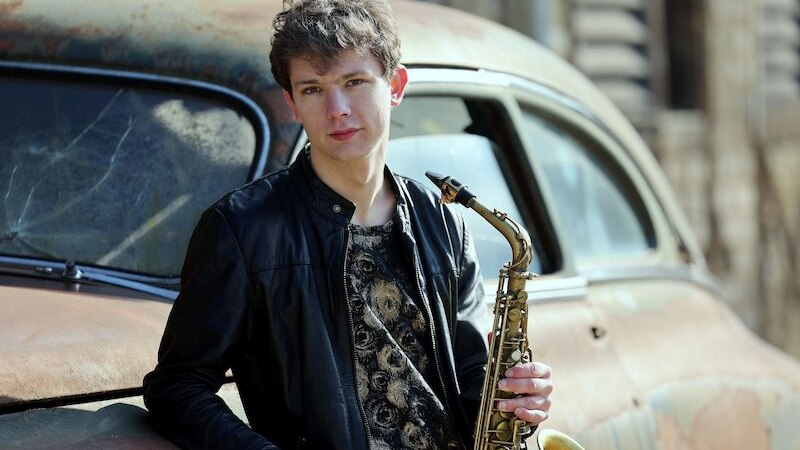 Ein junger Mann in einer Lederjacke hält ein Musikinstrument. Er schaut direkt in die Kamera, der Hintergrund ist unscharf., © Theaterhaus Stuttgart e.V. Ein junger Mann in einer Lederjacke hält ein Musikinstrument. Er schaut direkt in die Kamera, der Hintergrund ist unscharf., © Theaterhaus Stuttgart e.V.