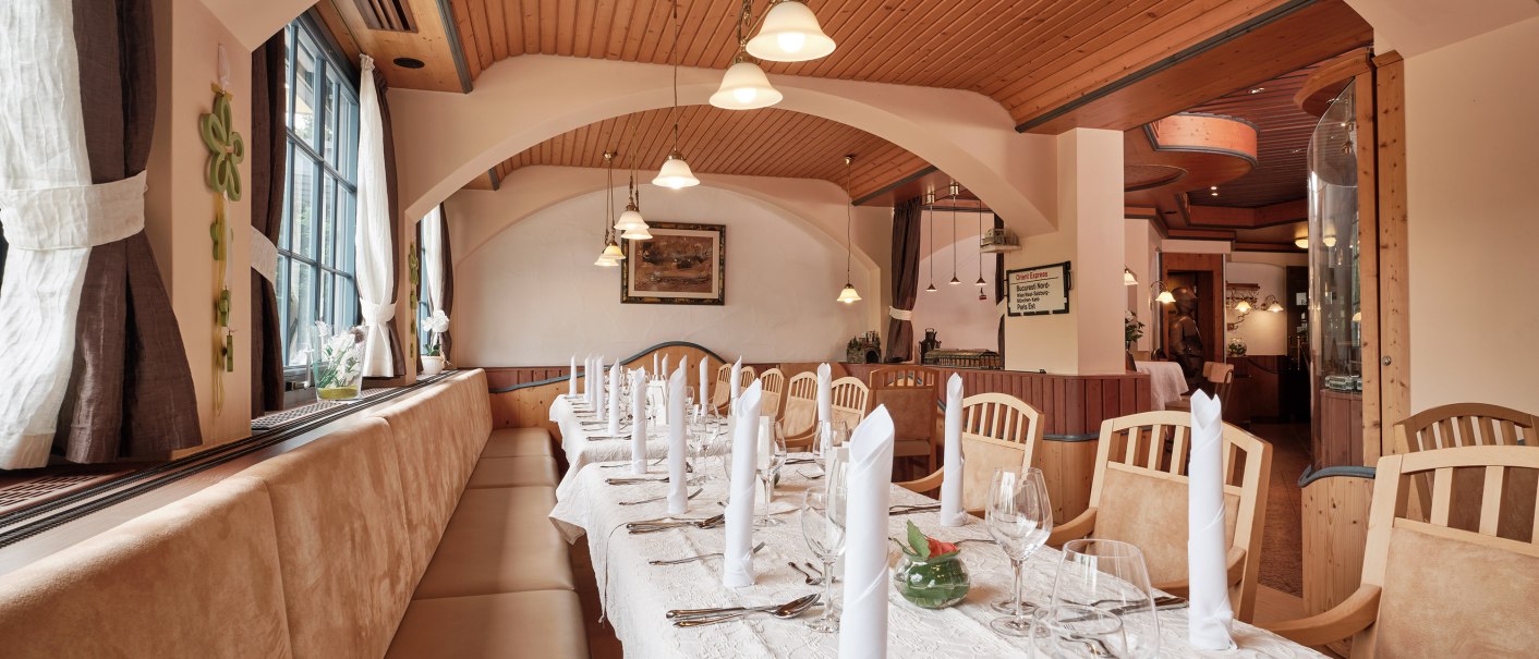 Ein stilvoll eingerichtetes Restaurant mit Holzbalkendecke, gedecktem Tisch und eleganten Stühlen. Große Fenster lassen viel Licht herein., © Badhotel Restaurant Stauferland