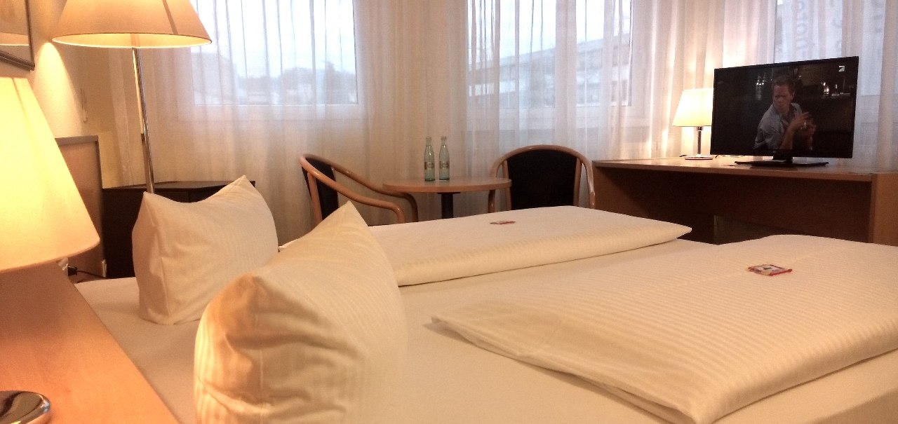 Gem&uuml;tliches Doppelzimmer mit Doppelbett, Schreibtisch, Stuhl und Fernseher. Gro&szlig;e Fenster mit Vorh&auml;ngen., &copy; Central Hotel