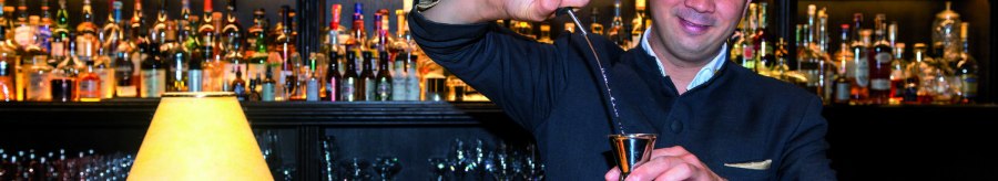 A bartender pours gin into a jigger. Numerous bottles can be seen on a shelf in the background., © © TMBW, Gregor Lengler