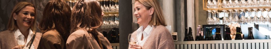 Four women are chatting in a stylish bar, holding champagne glasses. Glasses hang in the background, bottles stand on the bar., © Stuttgart-Marketing GmbH, wpsteinheisser Four women are chatting in a stylish bar, holding champagne glasses. Glasses hang in the background, bottles stand on the bar., © Stuttgart-Marketing GmbH, wpsteinheisser