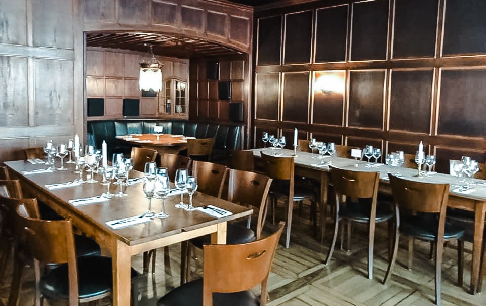 Elegantes Restaurant mit Holzw&auml;nden, gedeckten Tischen und Kerzenlicht. Dunkle Holzm&ouml;bel und eine gem&uuml;tliche Atmosph&auml;re dominieren den Raum., &copy; Weinstube Fr&ouml;hlich Verwaltungs GmbH