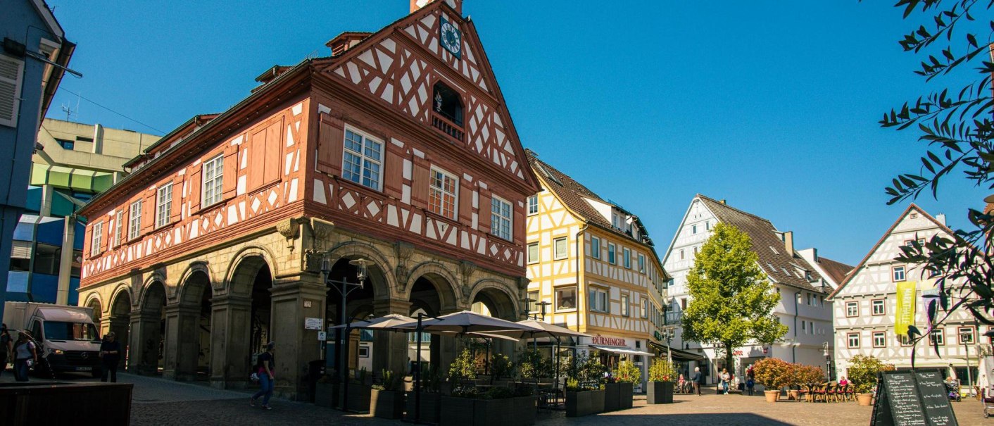 Historic half-timbered building on the market square in Waiblingen, surrounded by other half-timbered houses and an outdoor café in sunny weather., © Stuttgart-Marketing GmbH, Sarah Schmid Historic half-timbered building on the market square in Waiblingen, surrounded by other half-timbered houses and an outdoor café in sunny weather., © Stuttgart-Marketing GmbH, Sarah Schmid