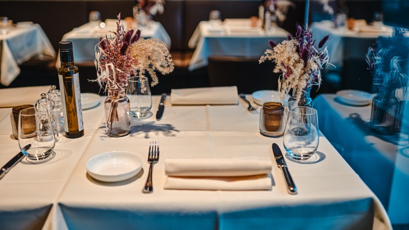 An elegantly laid table in a restaurant with white tablecloths, flower arrangements, glasses and cutlery., © Feinkost Böhm GmbH