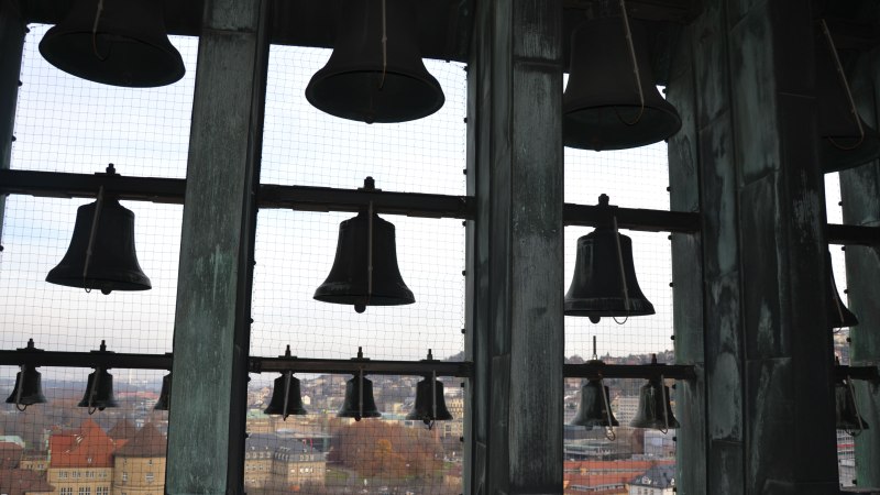 Glocken im Rathausturm mit Blick auf die Stadt im Hintergrund. Die Glocken sind in einem Gitterrahmen montiert, dahinter erstreckt sich die Stadt., &copy; Landeshauptstadt Stuttgart