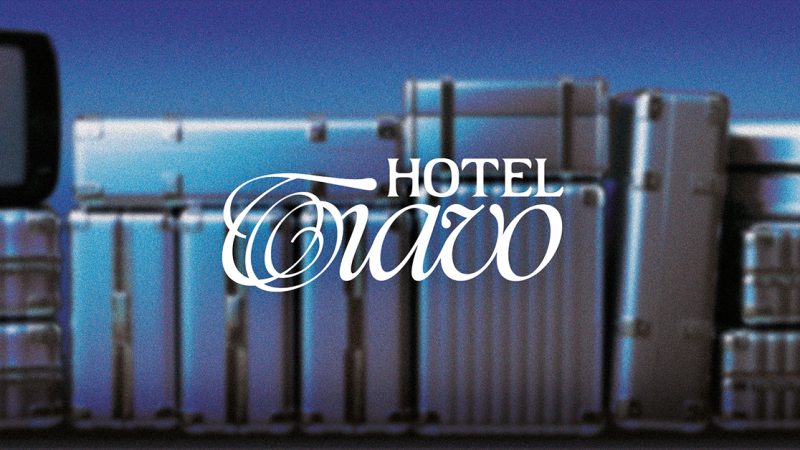 Das Logo von Hotel Tiavo ist vor einem Hintergrund mit mehreren Koffern zu sehen. Der Schriftzug ist elegant gestaltet., &copy; links im Bild