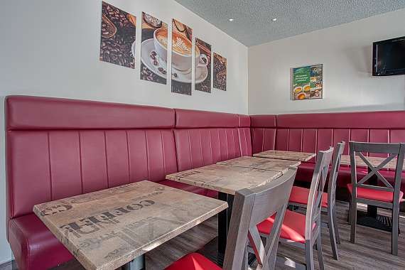 Breakfast room with red benches, wooden tables and chairs. Coffee pictures and a television hang on the wall., © Centro Hotels Breakfast room with red benches, wooden tables and chairs. Coffee pictures and a television hang on the wall., © Centro Hotels