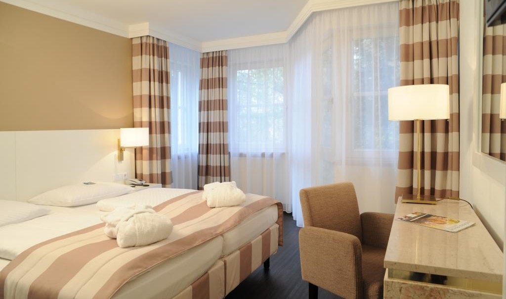 Elegant hotel room with double bed, striped curtains and a desk. Bright, inviting atmosphere with modern furnishings., &copy; relexa Waldhotel Schatten