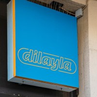 Blaues Schild mit gelber Aufschrift 'dilayla' an einer Geb&auml;udewand, daneben ein gr&uuml;ner Pfeil., &copy; Stuttgart Marketing GmbH, Sarah Schmid