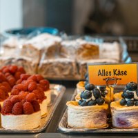 Cake in a display case, decorated with raspberries and blueberries. A sign reading 'All cheese' is visible., © SMG Stuttgart Marketing GmbH - Sarah Schmid Cake in a display case, decorated with raspberries and blueberries. A sign reading 'All cheese' is visible., © SMG Stuttgart Marketing GmbH - Sarah Schmid