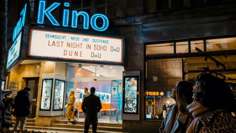 Eingang eines Kinos bei Nacht mit leuchtendem Schild. Menschen stehen davor und schauen nach oben. Filme: 'Last Night in Soho', 'Dune'., © SMG, Alwin Maigler
