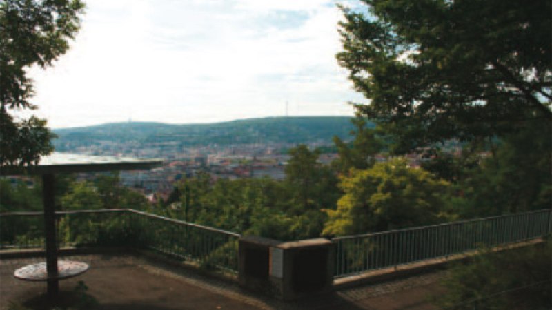 Aussichtsplattform mit Gel&auml;nder, umgeben von B&auml;umen, bietet Blick auf eine Stadt und H&uuml;gel im Hintergrund., &copy; Stuttgart-Marketing GmbH