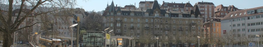 Marienplatz in Stuttgart mit Straßenbahn, modernen und historischen Gebäuden. Menschen sitzen auf Treppen, Bäume ohne Laub, sonniger Tag., © Stuttgart-Marketing GmbH