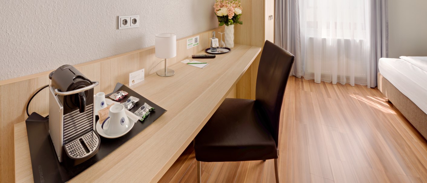 Modern single room with wooden floor, desk, chair, coffee machine and bed. Bright curtains let in daylight., © attimo Hotel Stuttgart Modern single room with wooden floor, desk, chair, coffee machine and bed. Bright curtains let in daylight., © attimo Hotel Stuttgart