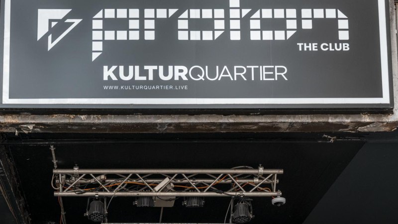 Schild von Proton The Club im Kulturquartier mit Website-Adresse. Darunter Beleuchtung und Metallstruktur sichtbar., © Stuttgart Marketing GmbH, Sarah Schmid