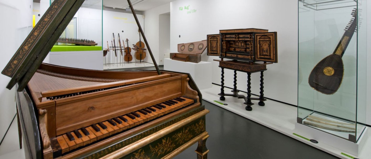 A museum exhibition room with historical musical instruments, including a harpsichord, a lute and string instruments in display cases., © Landesmuseum Württemberg