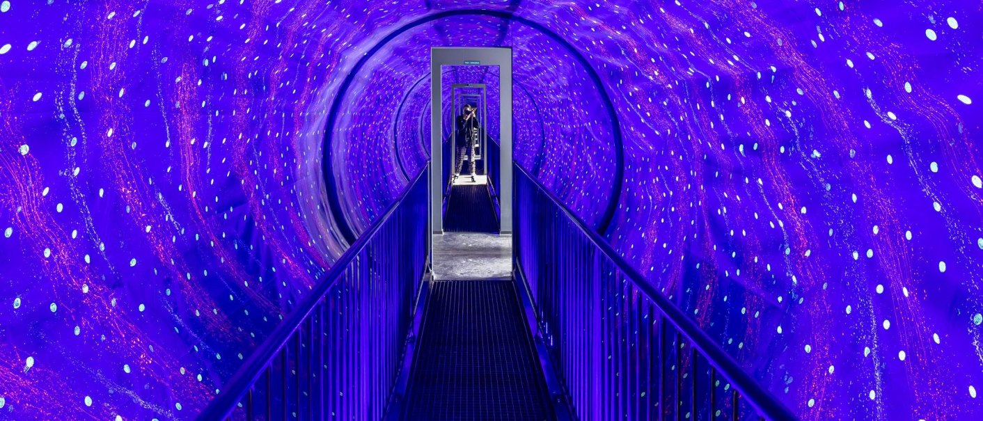 Ein beleuchteter Tunnel mit blauen und violetten Lichtern im Museum der Illusionen Stuttgart. Eine Person steht am Ende des Tunnels., © Stuttgart-Marketing GmbH, Sarah Schmid Ein beleuchteter Tunnel mit blauen und violetten Lichtern im Museum der Illusionen Stuttgart. Eine Person steht am Ende des Tunnels., © Stuttgart-Marketing GmbH, Sarah Schmid