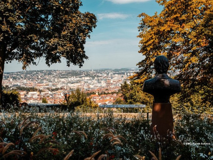 Eine Büste steht in einem blühenden Garten mit Blick auf eine Stadt im Tal, umrahmt von herbstlichen Bäumen., © Stuttgart Marketing GmbH Eine Büste steht in einem blühenden Garten mit Blick auf eine Stadt im Tal, umrahmt von herbstlichen Bäumen., © Stuttgart Marketing GmbH