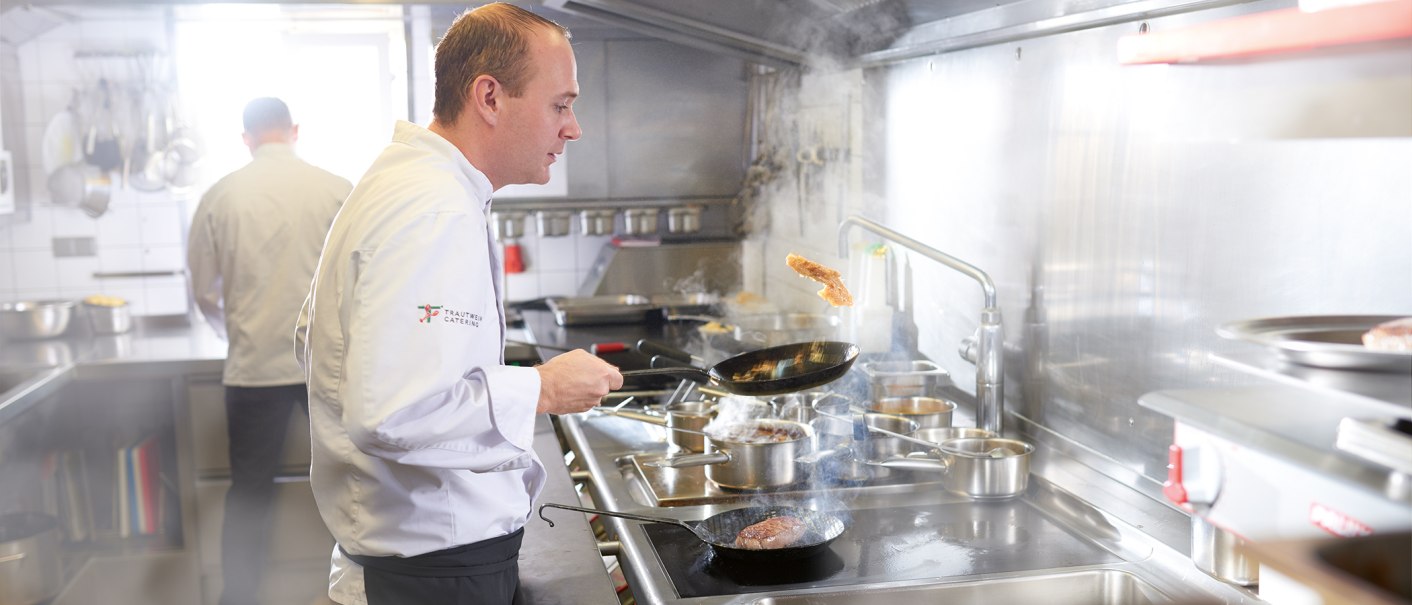 A chef in a white uniform fries meat in a pan in a professional kitchen. Another chef can be seen in the background., © SMG, Jean-Claude Winkler A chef in a white uniform fries meat in a pan in a professional kitchen. Another chef can be seen in the background., © SMG, Jean-Claude Winkler
