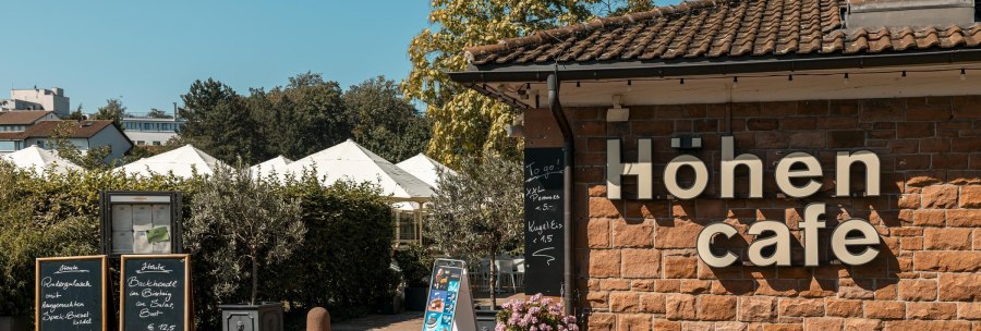 Das Höhen Café mit Schildern und Pflanzen im Außenbereich bei sonnigem Wetter., © SMG Stuttgart Marketing GmbH - Sarah Schmid