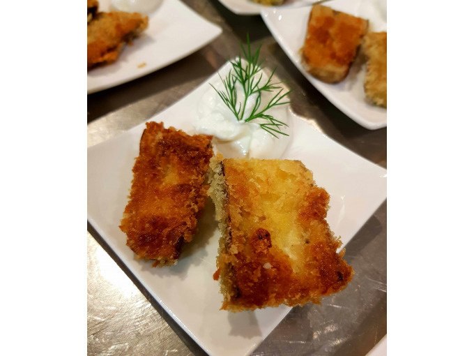 Two deep-fried, breaded pieces on a plate with white sauce and dill garnish., © Kultweine-Kochwelten-Kunstücke - Kochschule Sonja Lenz Two deep-fried, breaded pieces on a plate with white sauce and dill garnish., © Kultweine-Kochwelten-Kunstücke - Kochschule Sonja Lenz