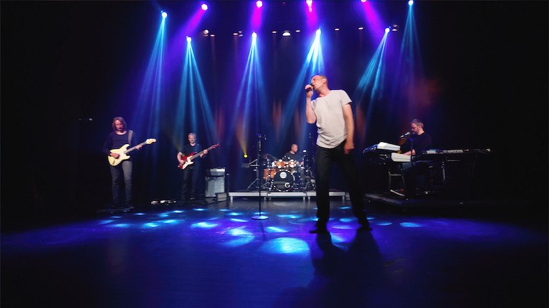 Eine Band spielt auf einer B&uuml;hne, beleuchtet von bunten Scheinwerfern. Der S&auml;nger steht im Vordergrund, Gitarristen und Schlagzeuger im Hintergrund., &copy; SKS Michael Russ GmbH