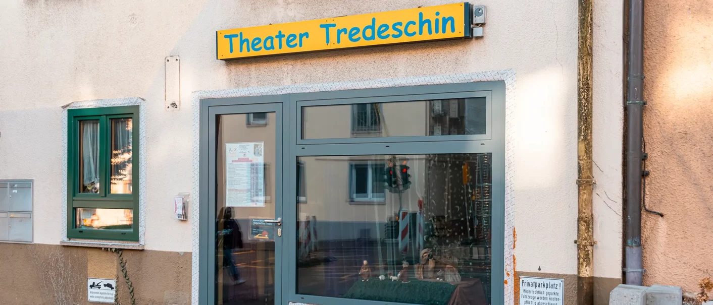 The entrance to the Tredeschin Theater, with a yellow sign above the door. A window with a curtain and a small display case are visible., &copy; SMG, Sarah Schmid