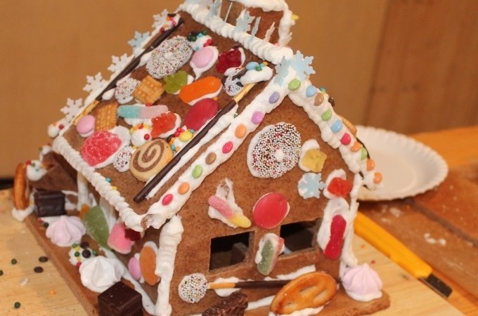 Ein liebevoll dekoriertes Lebkuchenhaus mit bunten S&uuml;&szlig;igkeiten und Zuckerguss auf einem Holztisch., &copy; Cool-Tours StattReisen