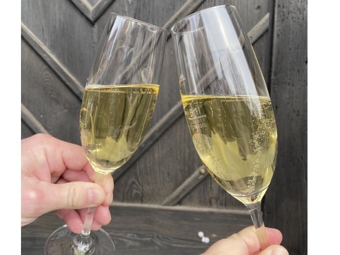 Zwei gefüllte Sektgläser stoßen vor einem dunklen Holzhintergrund an. Die Gläser sind mit prickelndem Sekt gefüllt., © Weingenuss Stuttgart Zwei gefüllte Sektgläser stoßen vor einem dunklen Holzhintergrund an. Die Gläser sind mit prickelndem Sekt gefüllt., © Weingenuss Stuttgart