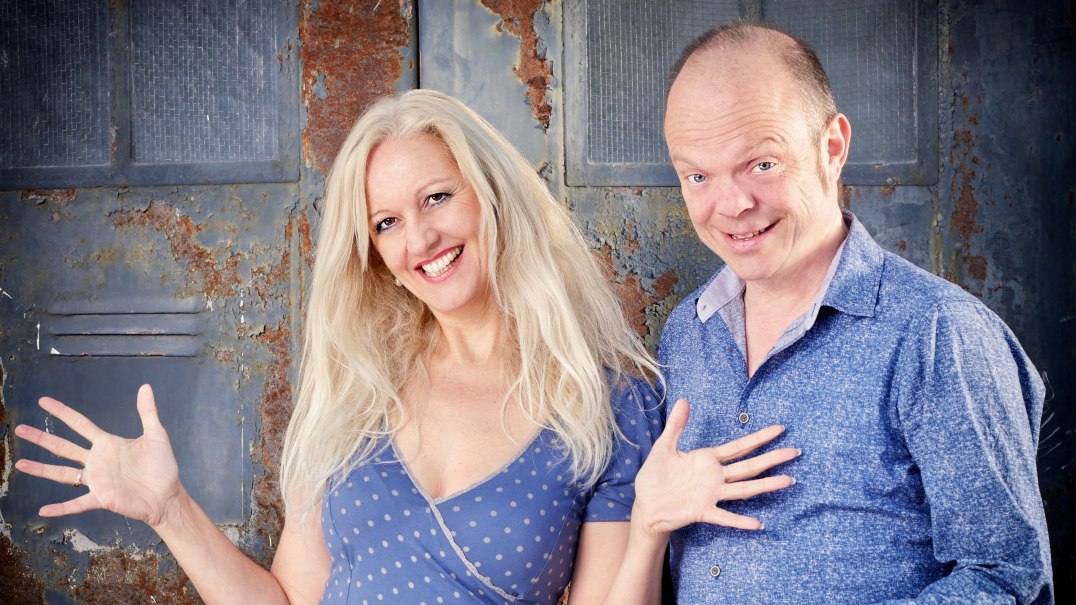 Zwei Personen lächeln vor einer rostigen Metallwand. Die Frau hat langes blondes Haar und trägt ein gepunktetes Kleid, der Mann ein blaues Hemd., © Veranstalter