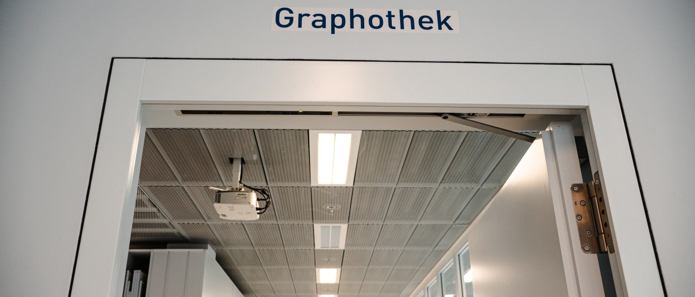 Entrance to the Graphothek with open door frame. Shelves and a suspended ceiling with lighting can be seen in the background., © Sarah Schmid Entrance to the Graphothek with open door frame. Shelves and a suspended ceiling with lighting can be seen in the background., © Sarah Schmid