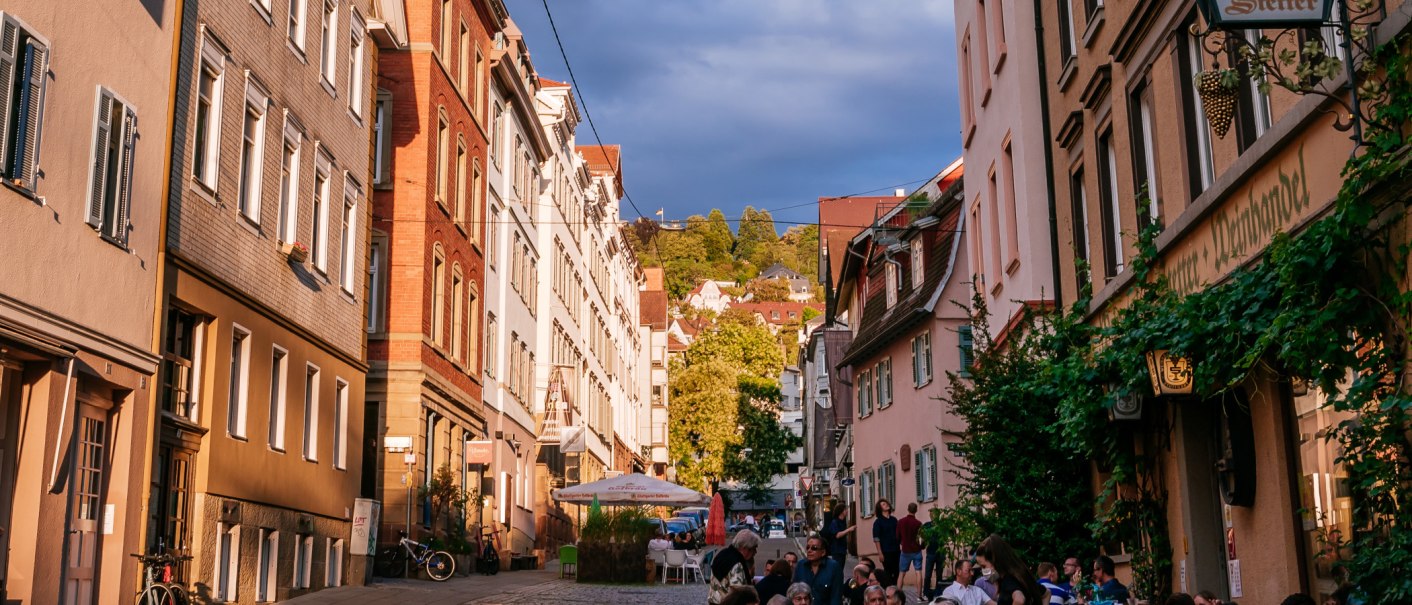 Straßenszene im Bohnenviertel mit historischen Gebäuden, Menschen in Straßencafés und grünem Laub. Die Abendsonne beleuchtet die Fassaden., © SMG Thomas Niedermüller Straßenszene im Bohnenviertel mit historischen Gebäuden, Menschen in Straßencafés und grünem Laub. Die Abendsonne beleuchtet die Fassaden., © SMG Thomas Niedermüller