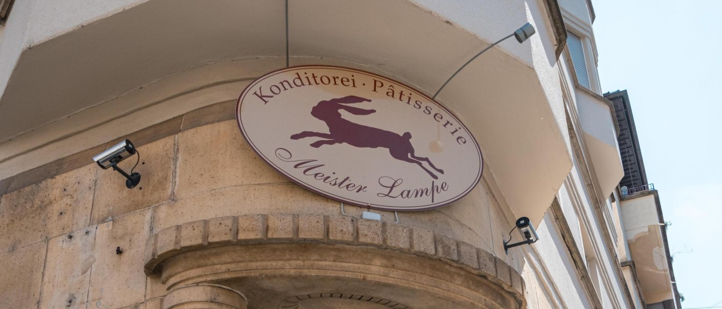 Schild der Konditorei 'Meister Lampe' mit springendem Hasen, an einer Geb&auml;udefassade montiert., &copy; SMG, Sarah Schmid
