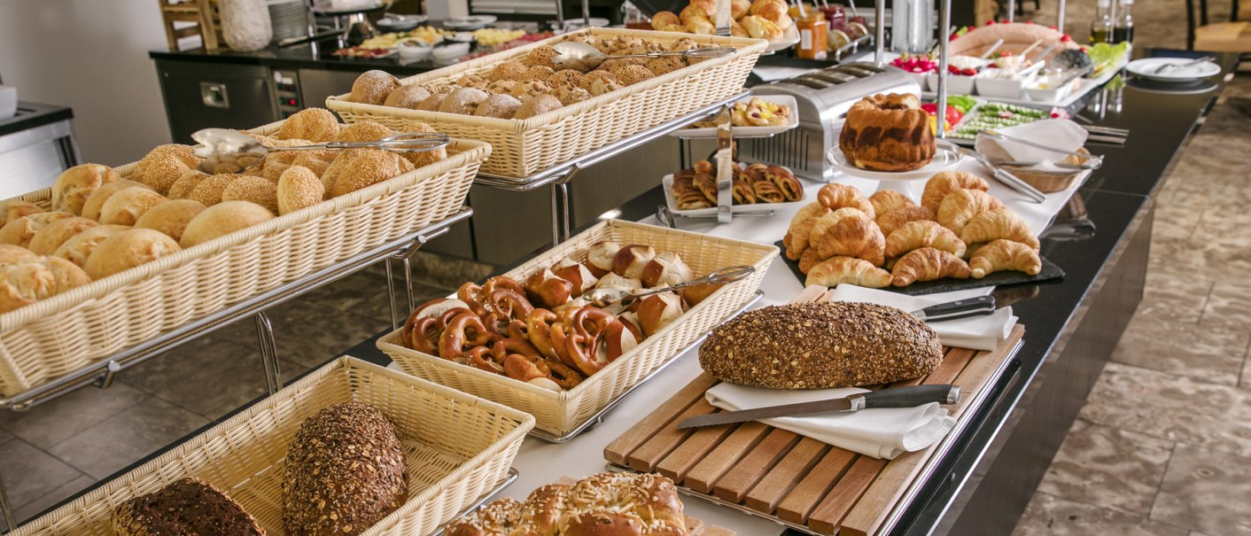 Ein Frühstücksbuffet mit einer Auswahl an Broten, Gebäck, Croissants und Säften auf einem Tisch., © ARCOTEL Hotels Ein Frühstücksbuffet mit einer Auswahl an Broten, Gebäck, Croissants und Säften auf einem Tisch., © ARCOTEL Hotels