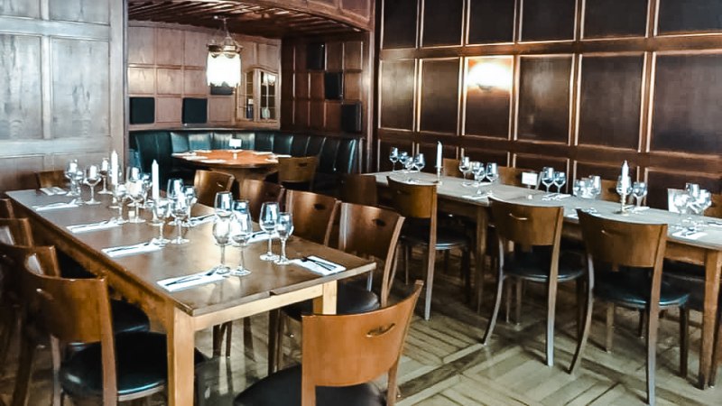 Elegantes Restaurant mit Holzwänden, gedeckten Tischen und Kerzenlicht. Dunkle Holzmöbel und eine gemütliche Atmosphäre dominieren den Raum., © Weinstube Fröhlich Verwaltungs GmbH