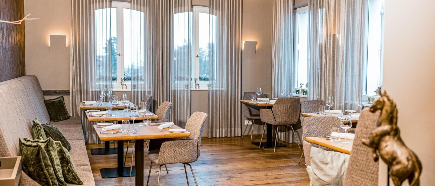 Elegantes Restaurant mit gedeckten Tischen, grauen Vorh&auml;ngen und Holzboden. Dezente Beleuchtung und stilvolle Dekoration schaffen eine gem&uuml;tliche Atmosph&auml;re., &copy; New Josch, Stuttgart