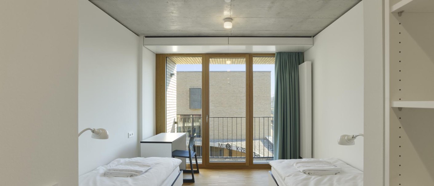 Modern twin room with hardwood floors, two single beds, a desk, and a large window with curtains., &copy; TOMAS